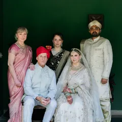 A formal family portrait from a cross-cultural wedding, with the bride's family from the West and the groom's family in traditional Indian wear.
