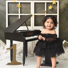 A classic first birthday portrait at the piano. The simple yet sophisticated set allows her sparkling personality and beautiful black dress to take center stage.