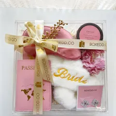 I believe in upgrading from the traditional 'shagun ka lifafa'. This acrylic box for the bride-to-be is filled with honeymoon essentials like a passport cover and comfy slippers.