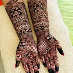 Personalization is key. Here, the groom's name 'ABHIJITH' is written across the bride's fingers. The rest of the design is a beautiful mix of modern geometric patterns and classic floral work.