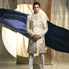 This elegant white sherwani features delicate floral and vine embroidery, offering a sophisticated and charming look for the modern groom.