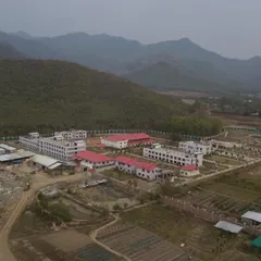 A real-world aerial view of the UNACCO School, showing the relationship between the completed buildings and the natural terrain we worked to preserve.