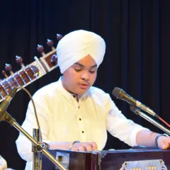 A young student fully immersed in his harmonium performance during a live concert. We provide opportunities for students of all ages to experience performing on stage.