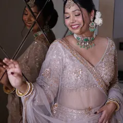A beautiful reflection shot capturing the bride's joyful smile. The soft hairstyle with fresh flowers adds a romantic touch to her overall look.