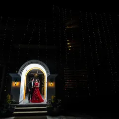 A single doorway, illuminated against the night, with a universe of fairy lights creating a magical canopy. This wide shot makes the couple the focal point of a grand, sparkling scene.