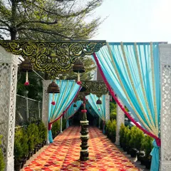 This vibrant entrance combines traditional elements like ornate overhead panels and hanging temple bells with a bright, festive color palette of sky blue and marigold yellow.