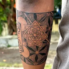 An intricate armband tattoo featuring Metatron's Cube, a powerful symbol in sacred geometry. The design is filled with complex patterns, creating a visually captivating piece that wraps around the forearm.