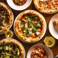 An overhead shot of multiple Neapolitan-style pizzas and appetizers. This "flat lay" style is highly effective for social media, showcasing variety and encouraging sharing.