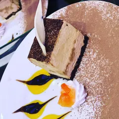 A beautifully plated tiramisu slice, dusted with cocoa powder and garnished with white chocolate. This classic Italian dessert is a testament to my expertise in Western and fusion bakery.