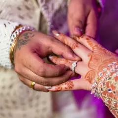 Another angle of the ring exchange, this time focusing on the groom placing the ring on the bride's finger, with her intricate henna on display.