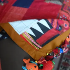 A close-up of the quilt's corner, highlighting the playful, handmade fish charms made from fabric scraps. These quirky details add a touch of fun and personality.