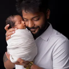 A father cradles his sleeping newborn against his chest. This tender portrait captures the feeling of protection and deep affection in the earliest days of fatherhood.