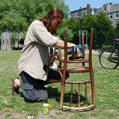 A volunteer repairs a wooden chair outdoors. We often take our workshops to parks and community spaces, combining the joy of fixing with fresh air.