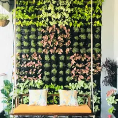 A close-up of a vertical garden on a balcony, showing the individual plant pockets before they have fully grown in. This system allows for creative patterns using different plant colors and textures, like the pink and green varieties seen here.