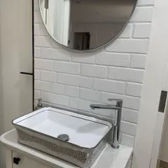 A close-up of the modern washbasin we added to a common passage area. The textured brick wall, patterned sink, and sleek chrome faucet create a stylish and convenient feature for guests and family members.