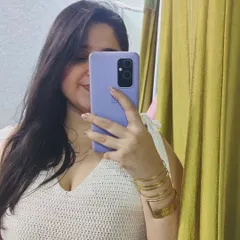 A mirror selfie showing off a white crochet top I made. It features a V-neck and shoulder ties, making it a trendy and comfortable piece for summer.