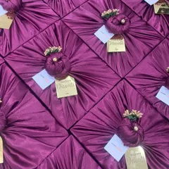 A beautiful array of Diwali gifts wrapped in rich purple satin fabric. The golden 'Happy Diwali' tags add a festive and luxurious finishing touch.