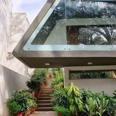 In this unique residential project, we used landscape to enhance a dramatic architectural feature. A flight of stairs leading up to a cantilevered canopy is flanked by a dense arrangement of potted plants, creating a lush, green ascent.