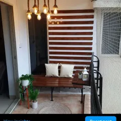 A full view of this cozy and modern balcony. The custom pinewood bench is paired with matching wall slats and beautiful rope lighting for a complete look.
