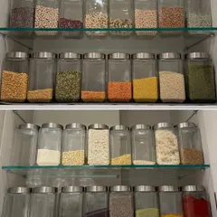This is what a fully stocked and organized pantry looks like. We categorize dals, grains, and spices on separate shelves, using clear jars so you can do a quick visual audit before you go shopping.