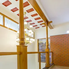 This view showcases a blend of traditional and modern elements: carved wooden columns, a patterned filler slab ceiling, and an ornate chandelier, all working together in a double-height space.