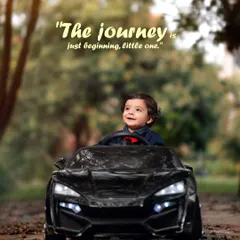 A toddler enjoys a ride in a miniature black sports car on a path covered in autumn leaves. This shot captures the joy and adventure of childhood exploration.