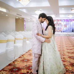 A quiet moment before the guests arrive. This wide shot captures the couple in an intimate pose within the grand, empty banquet hall, creating a sense of peace and anticipation before their engagement party.