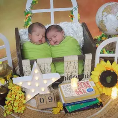 These twin boys are ready to take on the world together. This creative setup includes a globe, books, and sunflowers, creating a fun and adventurous theme for their newborn portraits.