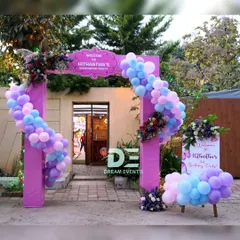 A grand entrance for an enchanted party, featuring a large purple arch decorated with pastel balloons and floral arrangements.