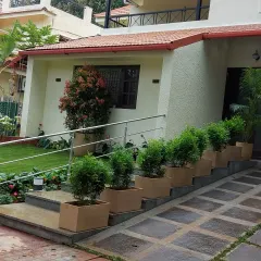 A practical and accessible entrance combining stairs and a ramp. The design is enhanced by a series of matching planters with topiary shrubs, adding a touch of formal elegance.