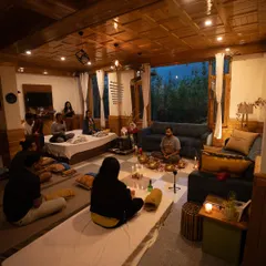An intimate Full Moon meditation session held in a cozy, wood-paneled room. The candlelight and focused group energy create a truly special and uplifting atmosphere for healing and connection.