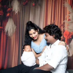 A beautiful family portrait with parents looking lovingly at their newborn baby, who is swaddled and resting.