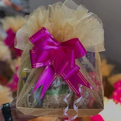 A simple yet elegant welcome hamper, beautifully wrapped in net with a large pink bow. It's filled with snacks and essentials to make wedding guests feel right at home.