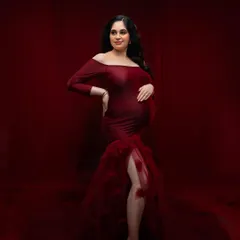 A full-length portrait showcasing a magnificent off-the-shoulder red gown. The rich color and mermaid-style tulle train create a classic, high-impact look that is both elegant and unforgettable.