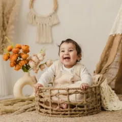 That big, gummy smile is everything. This baby is having a great time sitting in a wicker basket during her simple, boho-themed studio session.