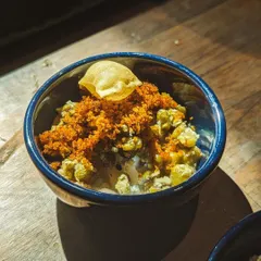 Kanji Payar, or rice congee with green gram, is the ultimate comfort food. I serve it here in a tasting bowl, topped with crispy papadum and a flavorful dry prawn chammandi. It’s a nutritious and flavorful appetizer.