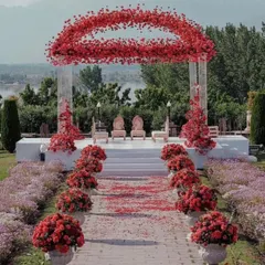 For a bold and passionate statement, we designed this stunning outdoor mandap using thousands of red roses. The circular floral arch creates a dramatic focal point, perfectly framing the couple against a beautiful natural landscape. This is a great example of our custom floral architecture.