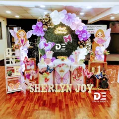 A whimsical fairy and butterfly theme for Sherlyn Joy's first birthday. I combined a green hedge backdrop with a purple balloon arch, fairy cutouts, and marquee letters to create this magical garden party look.