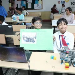 Two students proudly present their robotics project and the poster they created to explain it. Our program encourages not just building but also developing communication and presentation skills.