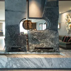 A home's entrance should be an evocative experience. We designed this majestic water feature from massive, naturally split stone slabs, etched with Pali script and adorned with brass 'Khadau' sandals to create a serene and symbolic threshold that offers blessings upon entry.