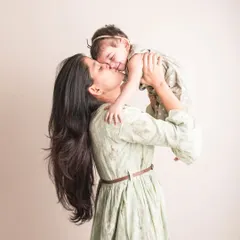 A kiss filled with pure adoration. This beautiful shot of a mother lifting her daughter up is overflowing with joy and affection.