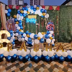 A superhero-themed birthday party featuring both Batman and Captain America. The setup includes a balloon ring against a green wall, character cutouts, a 'Happy Birthday' neon sign, light-up number '6', and balloon letters spelling the name 'PRAHAV'.