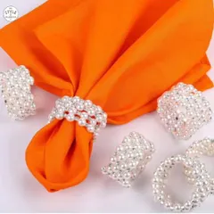 Timeless elegance is all in the details. These white pearl napkin rings add a touch of classic sophistication to any dining experience, shown here beautifully complementing a vibrant orange napkin for a modern twist.
