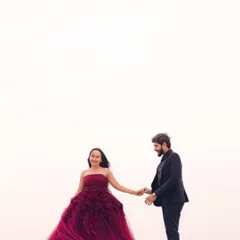 A sweet, candid moment between the couple. The flowing tulle of the maroon gown adds a sense of movement and romance to the shot.