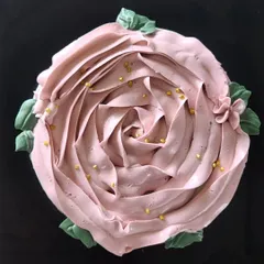 A top down view of my vanilla and strawberry cake. The frosting is piped to look like a large pink rose, with small green leaves and a sprinkle of gold dust for an elegant, floral finish.