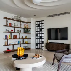 Another view of the living space with the sculptural swirl ceiling. Here, you can see the custom-designed wooden bookshelf and the organically shaped coffee table, which continue the home's theme of unique, art-like furniture and fixtures.