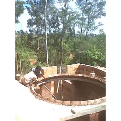 A mason skillfully constructing a circular brick dome for the Professor's Residence. This showcases the high level of craftsmanship involved in our projects and our use of traditional building techniques like domes and vaults.