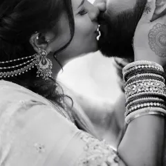 An intimate black and white close-up of a kiss, focusing on the details of the bride's jewelry and the couple's embrace.