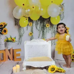 This candid shot captures a playful moment during a sunflower themed first birthday, with the little one sticking her tongue out, full of personality.