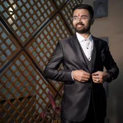 A dapper portrait of the groom. Dressed in a sharp black suit, he looks happy and ready for the big day, captured in a moment of candid confidence.